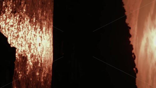 Video - A dramatic sunset view showing a dark cliff silhouette with golden sunlight shimmering across the sea. Vertical