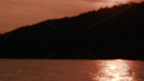 Video - A dramatic sunset view showing a dark cliff silhouette with golden sunlight shimmering across the sea