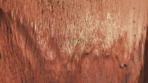 Video - Close up of gentle waves washing over the sand in golden evening light. Vertical