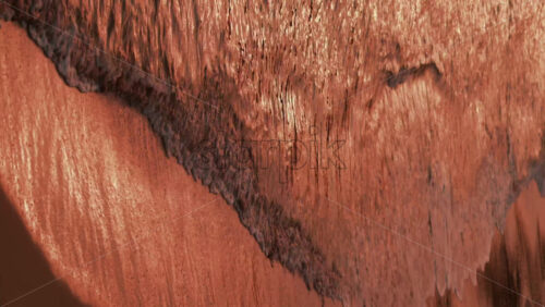 Video - Close up of gentle waves washing over the sand in golden evening light. Vertical