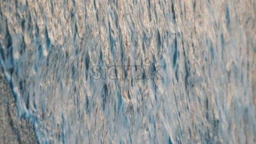 Video - Close up of gentle waves washing over the sand in golden evening light. Vertical