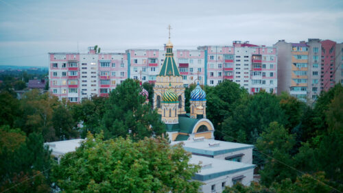 Video - Aerial view of a colorful Orthodox church with onion domes, framed by residential apartment blocks and greenery
