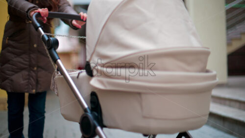 Video - Rear view of a beige baby stroller moving along a narrow alley with yellow and brown walls