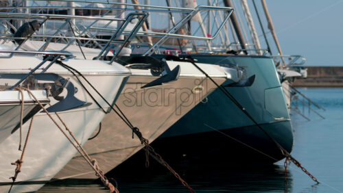 Video - Side view of several luxury yachts moored side by side with ropes and anchors visible