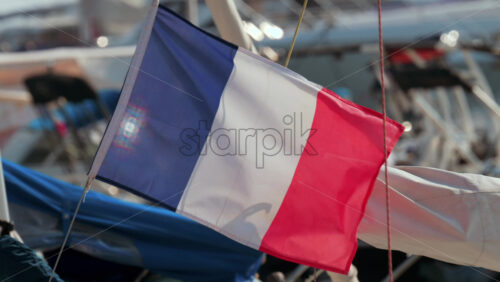 Video - Close up of the French flag fluttering gently near boats in a marina