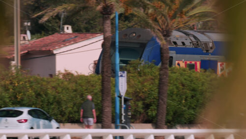 Video - Cannes, France - October 12, 2025: A regional SNCF train travels along the coastal tracks near Cannes, with palm trees and beachgoers visible below