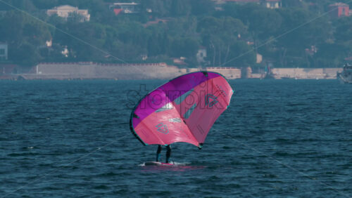 Video - Cannes, France - October 12, 2025: A man practices wing foiling on the open sea using a bright pink sail