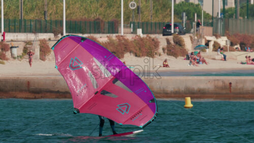 Video - Cannes, France - October 12, 2025: A man practices wing foiling on the open sea using a bright pink sail