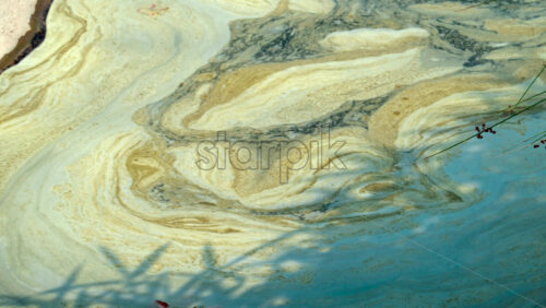 Video - Close up of dirty water with swirling yellowish foam patterns