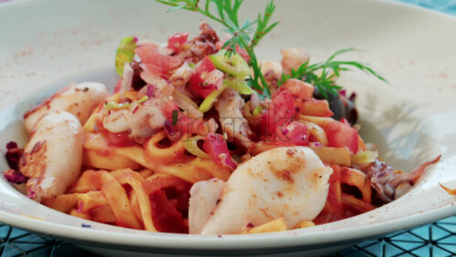 Video - Close up of a seafood pasta dish with shrimp, squid, and tomato sauce, beautifully plated at a Mediterranean restaurant