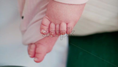 Video - Close up shot of a baby's feet resting on a bench, wearing soft pink clothes with small heart patterns