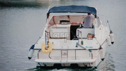 Video - Cannes, France - October 12, 2025: A man prepares his small motorboat to leave the marina, surrounded by still water and large yachts in the background