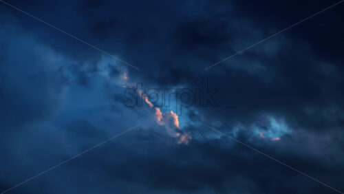 Video - Moody dark blue clouds move across the sky at dusk, revealing a streak of warm light through the center