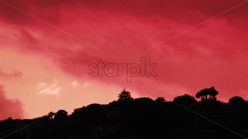 Video - Silhouette of trees and hills under an intense red sunset sky