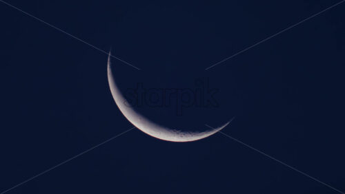 Video - Close up of a thin crescent moon glowing against a deep blue night sky
