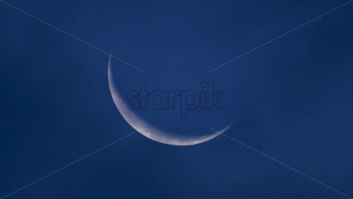 Video - Close up of a thin crescent moon glowing against a deep blue night sky