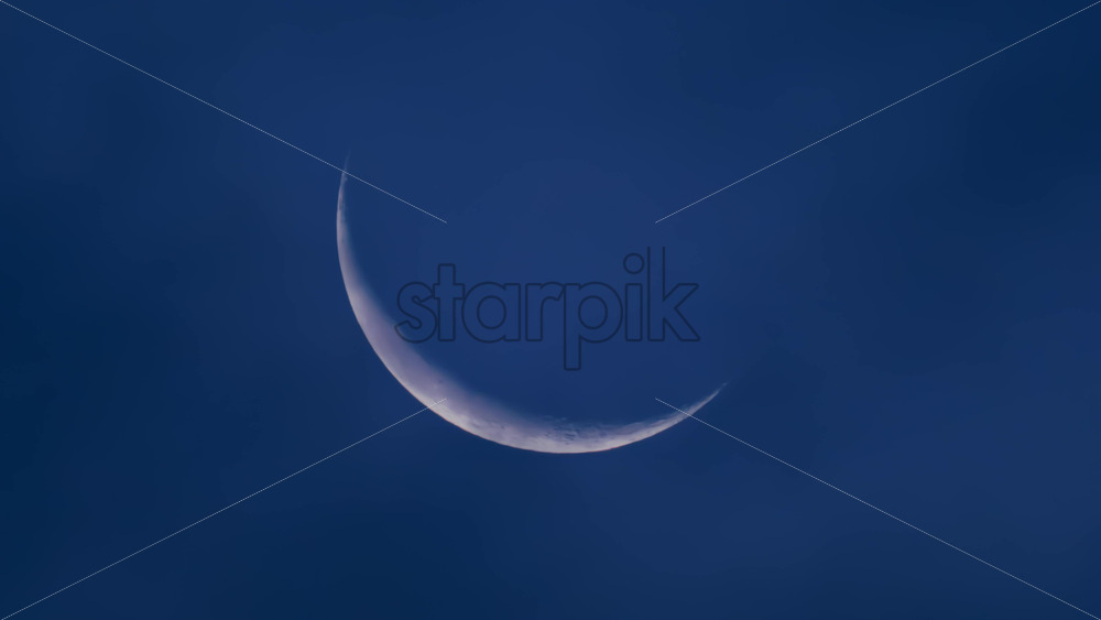 Video - Close up of a thin crescent moon glowing against a deep blue night sky