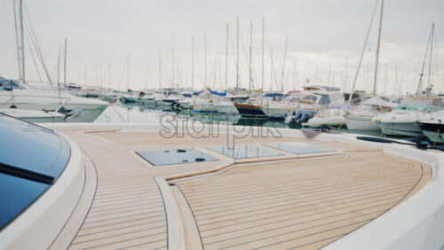 Video - A luxury yacht deck overlooking a peaceful marina filled with sailboats and motor yachts under soft daylight