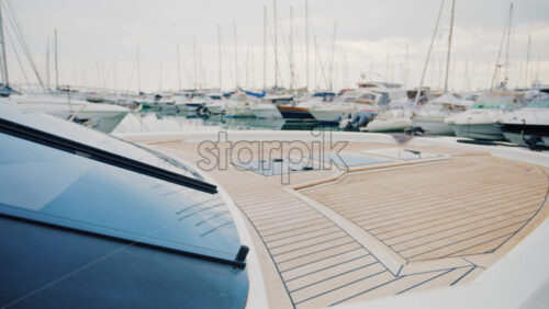 Video - A luxury yacht deck overlooking a peaceful marina filled with sailboats and motor yachts under soft daylight
