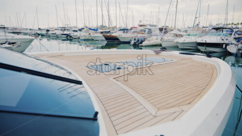 Video - A luxury yacht deck overlooking a peaceful marina filled with sailboats and motor yachts under soft daylight