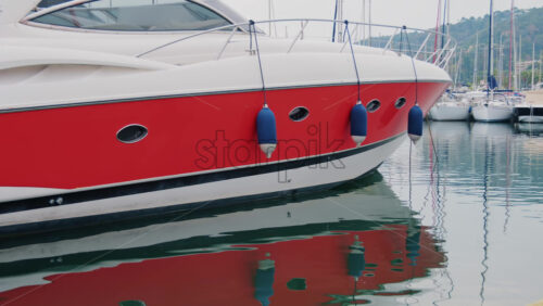 Video - Modern red and white yacht docked in calm marina waters with clear reflections
