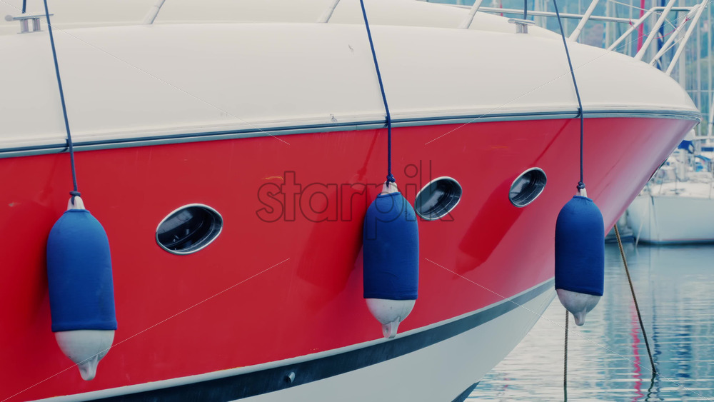 Video - Modern red and white yacht docked in calm marina waters with clear reflections