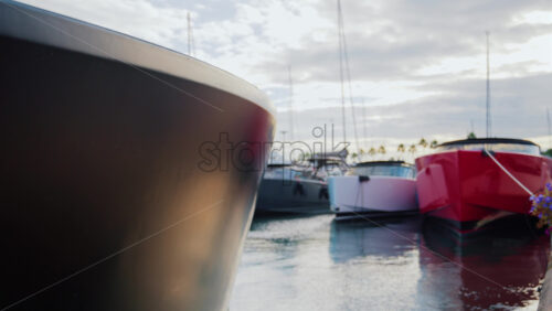 Video - Close up of sleek luxury boats with red and black hulls moored in a marina at sunset