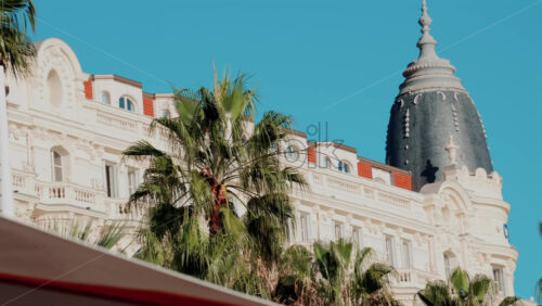 Video - Beautiful facade of a historic luxury hotel framed by palm trees against a clear blue sky