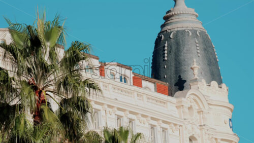 Video - Beautiful facade of a historic luxury hotel framed by palm trees against a clear blue sky