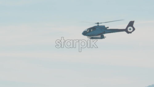 Video - Close up of helicopter gliding above layered blue mountains under soft daylight