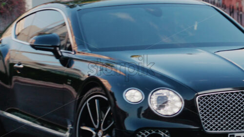 Video - Cannes, France - October 3, 2025: View of a black Bentley car with polished chrome grille and reflections moving on the street