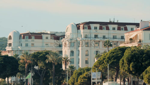 Video - Cannes, France - October 13, 2025: Elegant white hotel building surrounded by palm trees on the Croisette promenade