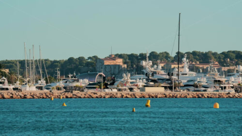 Video - Dozens of luxury yachts anchored in thePort Pierre Canto in Cannes, with scenic coastal architecture and calm blue sea