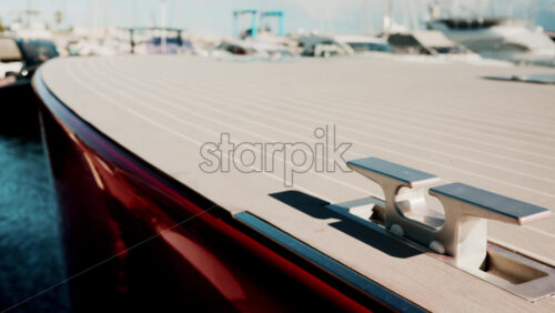 Video - Close up of a sleek red luxury boat deck with metallic cleat, shot in bright sunlight at a marina