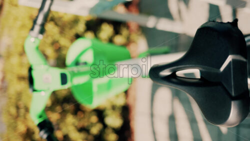 Video - Close up of a green electric bicycle with modern design, parked outdoors under natural light. Vertical