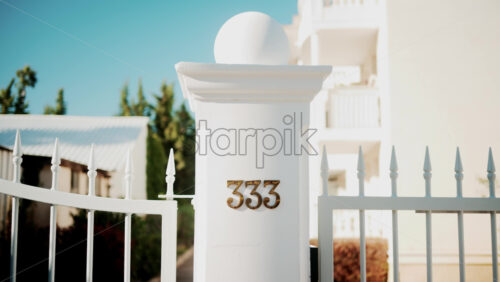 Video - Golden metallic number 333 mounted on a white wall in sunlight