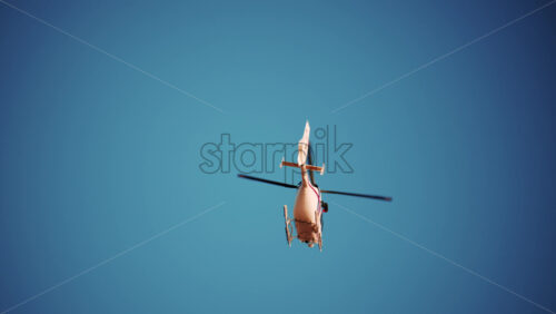 Video - View of a white helicopter flying across a blue sky framed by blurred palm trees