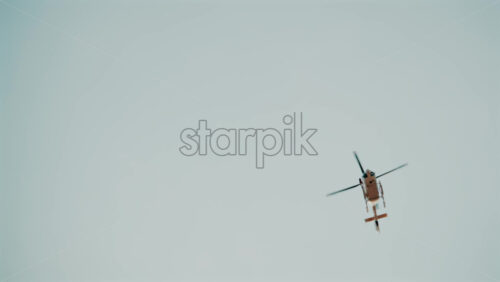 Video - Distant view of a helicopter flying alone against a pale sky