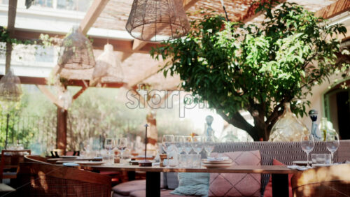Video - Interior of a chic outdoor restaurant with wooden furniture, glassware, and soft light