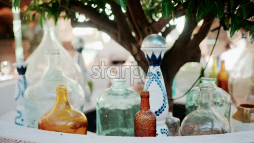 Video - Colorful vintage glass bottles and decanters illuminated by soft sunlight outdoors