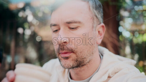 Video - Close up of a man sipping coffee in natural sunlight at a cozy outdoor cafe