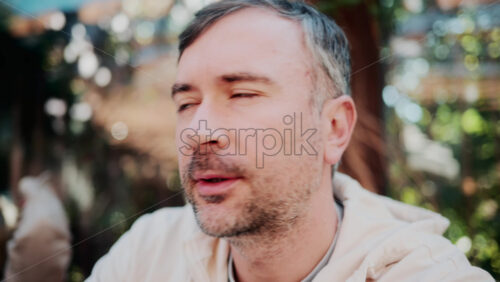 Video - Close up of a man talking coffee in natural sunlight at a cozy outdoor cafe