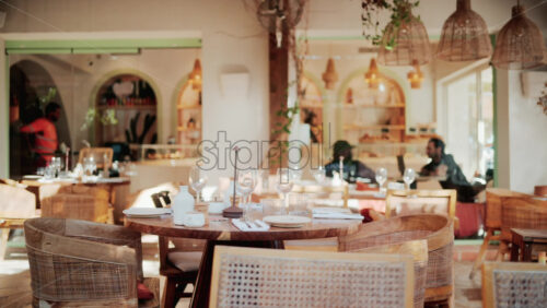 Video - Warm and elegant restaurant interior with wooden chairs, wine glasses, and natural light