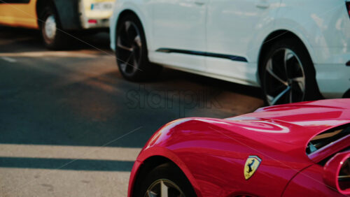 Video - Cannes, France - October 3, 2025: Red convertible Ferrari car driving through sunny city streets with palm trees and traffic