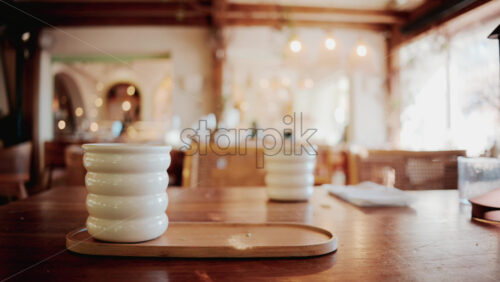 Video - White ceramic cup of green matcha latte on a wooden table in a bright outdoor cafe