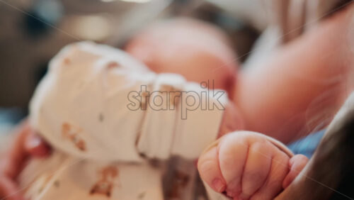 Video - Tender moment of a mother holding her newborn baby dressed in patterned white pajamas
