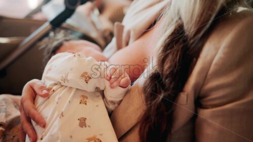 Video - Tender moment of a mother holding her newborn baby dressed in patterned white pajamas