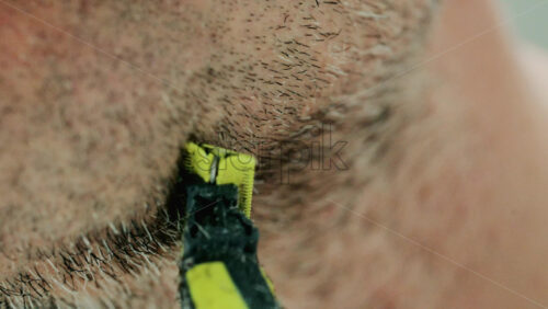 Video - Close up of a man using an electric razor to trim facial hair in the bathroom