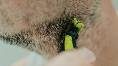 Video - Close up of a man using an electric razor to trim facial hair in the bathroom