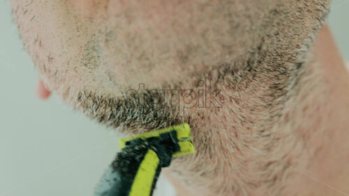 Video - Close up of a man using an electric razor to trim facial hair in the bathroom